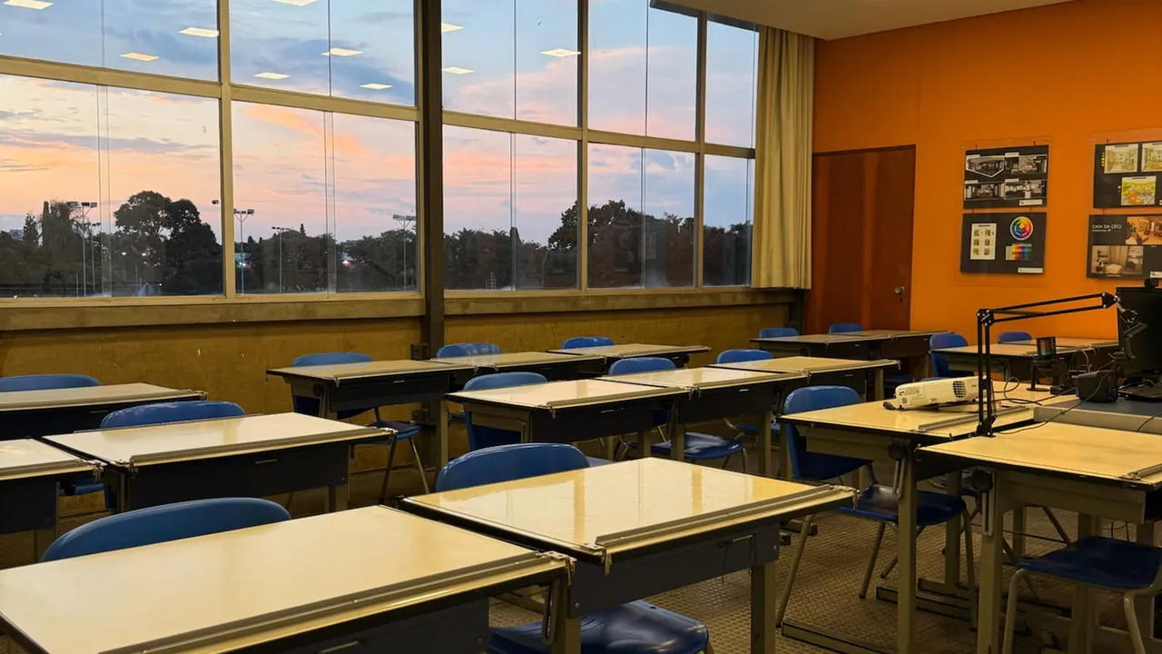 Sala de aula ampla com janelas e vista externa ao pôr do sol